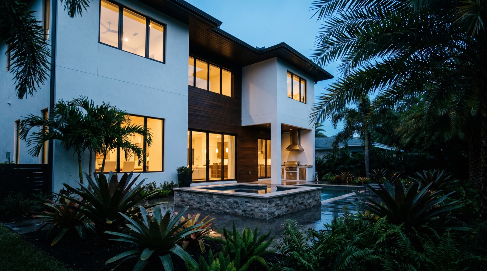 Illustrative image, not the actual property. A modern two-story luxury duplex with a lit courtyard and hot tub at dusk